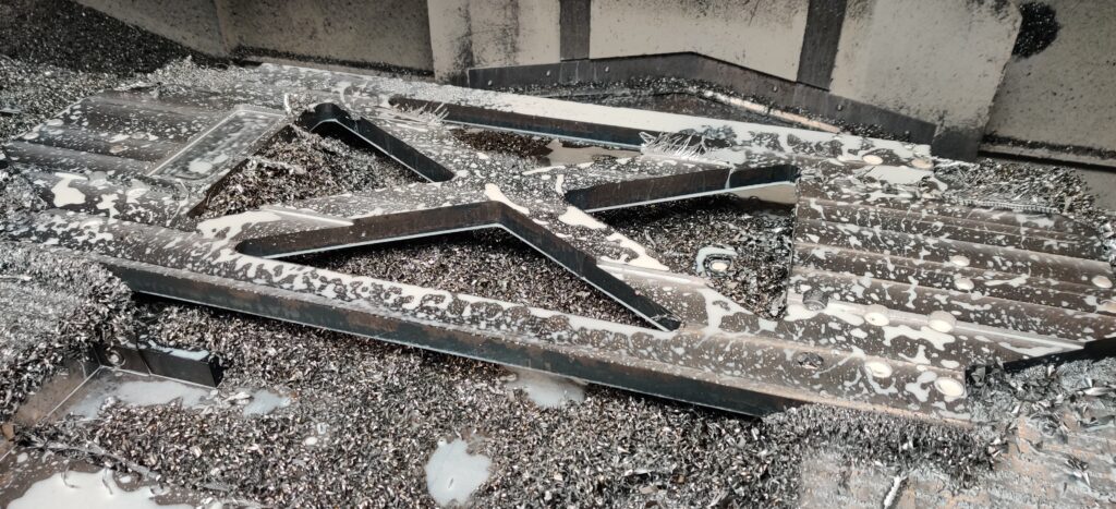 A steel lasered part. Clamped on 2 permanent magnet tables. CNC milled, drilled and threated.